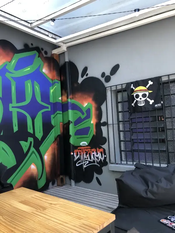 Parede com grafite verde e a bandeira dos Chapéus de Palha, de One Piece, na janela